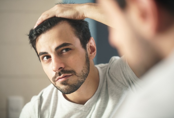 man checking for hair loss in mirror